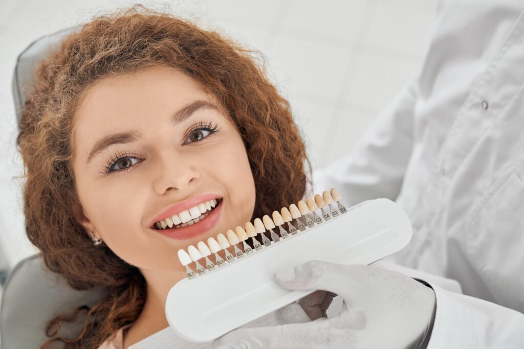 woman smiling while male dentist keeping teeth color range